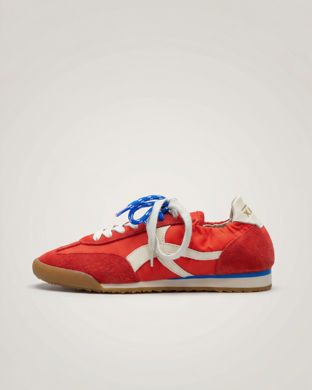 Red sneaker with white logo and blue laces on a light gray background