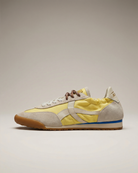Sneaker with yellow and beige design on a neutral background