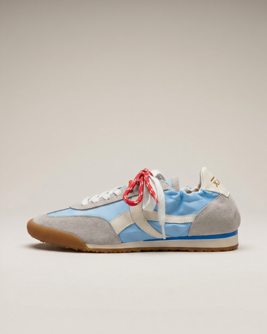 Sneaker with gray, blue, and white color scheme on a beige background